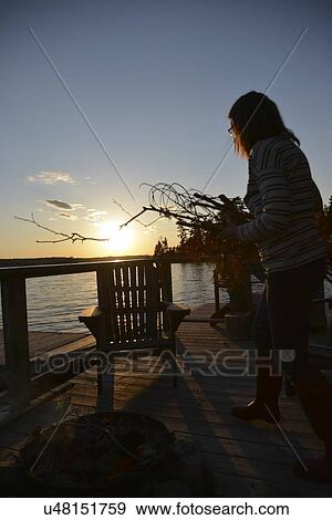 Woman standing on a patio carrying firewood, Lake of The Woods, Keewatin, Ontario, Canada View Large Photo Image Stock Photo - Woman standing on a patio carrying firewood, Lake of The Woods, Keewatin, Ontario, Canada. Fotosearch