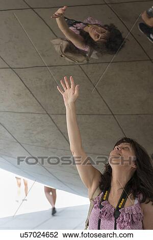 Stock Image - Woman touching her reflection on Cloud Gate, Millennium Park, Chicago, Cook County, Illinois, USA. Fotosearch