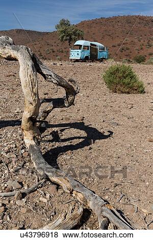 Abandoned bright blue dormobile van, propped up on rocky terrain of desert framed by tree branch on ground, hills beyond in bright blue sky, Palmwag Concession, Damaraland, Namibia, South West Africa View Large Photo Image Stock Photo - Abandoned bright blue dormobile van, propped up on rocky terrain of desert framed by tree branch on ground, hills beyond in bright blue sky, Palmwag Concession, Damaraland, Namibia, South West Africa. Fotosearch