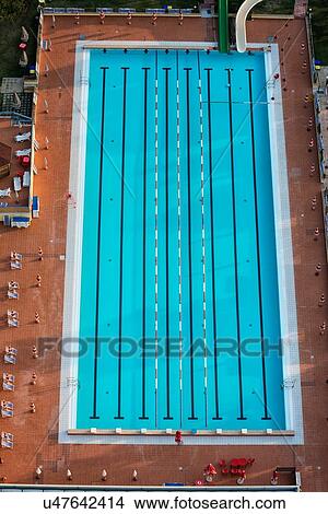Aerial view of athlete's swimming pool with channels marked by black lines, and red and white dividers, with blue deck chairs on red tiles alongside, early morning sunshine, Umbria, Italy View Large Photo Image Picture - Aerial view of athlete's swimming pool with channels marked by black lines, and red and white dividers, with blue deck chairs on red tiles alongside, early morning sunshine, Umbria, Italy. Fotosearch