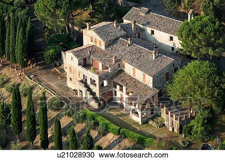 Stock Image - Aerial view of beautiful old stone farmhouse with surrounding cypress trees, in early morning sunshine, Middle Tiber Valley, Umbria, Italy. Fotosearch
