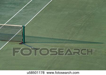 Stock Photo - Aerial view of green tennis court, close up detail showing part of net, net shadow, white marker lines, and sweeping brush lying on the court, at athletic centre, in early morning sunshine, Todi, Umbria, Italy. Fotosearch