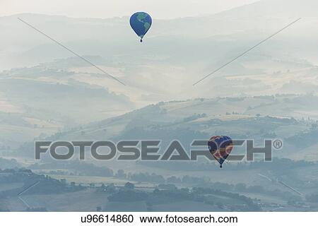 Aerial view of layered hills of the Middle Tiber Valley in early morning hazy sunshine, with two hot air balloons floating above, Todi, Umbria, Italy View Large Photo Image Stock Image - Aerial view of layered hills of the Middle Tiber Valley in early morning hazy sunshine, with two hot air balloons floating above, Todi, Umbria, Italy. Fotosearch