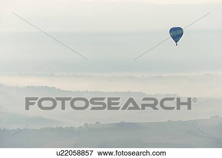Aerial view of layered hills of the Middle Tiber Valley in early morning hazy sunshine, with a hot air balloon floating above, Todi, Umbria, Italy View Large Photo Image Stock Photo - Aerial view of layered hills of the Middle Tiber Valley in early morning hazy sunshine, with a hot air balloon floating above, Todi, Umbria, Italy. Fotosearch