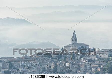 Aerial view of medieval city of Todi with church and spire of San Fortunato church and layered hills of the Middle Tiber Valley beyond, in early morning hazy sunshine, Todi, Umbria, Italy View Large Photo Image Stock Image - Aerial view of medieval city of Todi with church and spire of San Fortunato church and layered hills of the Middle Tiber Valley beyond, in early morning hazy sunshine, Todi, Umbria, Italy. Fotosearch