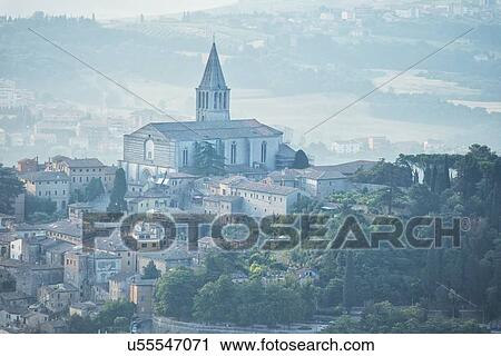 Stock Image - Aerial view of medieval city of Todi with church and spire of San Fortunato church and countryside beyond, in early morning sunshine, Todi, Umbria, Italy. Fotosearch