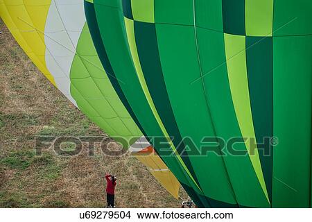 Close up of multicoloured hot air balloons inflated and about to launch with colourful overlap of patterned envelopes, with photographer alongside, seen from air, Todi Mongolfiere Hot Air Balloon Festival, Umbria, Italy View Large Photo Image Picture - Close up of multicoloured hot air balloons inflated and about to launch with colourful overlap of patterned envelopes, with photographer alongside, seen from air, Todi Mongolfiere Hot Air Balloon Festival, Umbria, Italy. Fotosearch