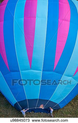 Close up of multicoloured hot air balloon inflating, held by two men as flame is heating envelope, seen from air, close up view, Todi Mongolfiere Hot Air Balloon Festival, Umbria, Italy View Large Photo Image Stock Image - Close up of multicoloured hot air balloon inflating, held by two men as flame is heating envelope, seen from air, close up view, Todi Mongolfiere Hot Air Balloon Festival, Umbria, Italy. Fotosearch