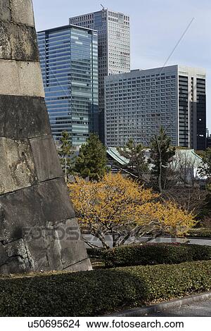 Picture - East Garden wall of Tengshudai Donjon Base built in traditional 19th century Shogun Japanese style, landscaped gardens and modern high rise buildings beyond, Imperial Palace, Tokyo, Japan. Fotosearch