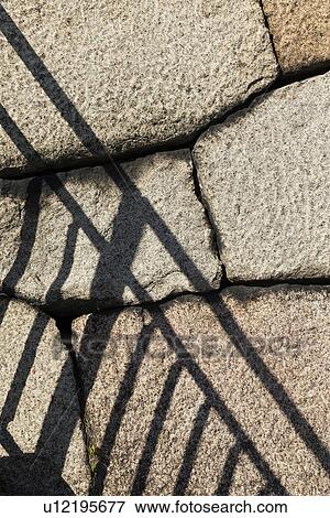 Stock Photo - East Garden wall of Tengshudai Donjon Base built in traditional 19th century Shogun Japanese style, with banister railing shadow in contrast against huge stonework, detail, Imperial Palace, Tokyo, Japan. Fotosearch