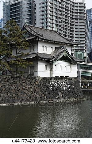 East Gate guard house and wall built in traditional 19th century Shogun Japanese style, reflected in moat, and modern high rise buildings beyond, Imperial Palace, Tokyo, Japan View Large Photo Image Stock Image - East Gate guard house and wall built in traditional 19th century Shogun Japanese style, reflected in moat, and modern high rise buildings beyond, Imperial Palace, Tokyo, Japan. Fotosearch