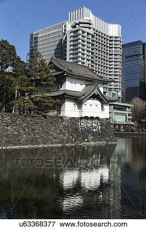East Gate guard house and wall built in traditional 19th century Shogun Japanese style, reflected in moat, and modern high rise buildings beyond, sunny day with blue sky, Imperial Palace, Tokyo, Japan View Large Photo Image Stock Photo - East Gate guard house and wall built in traditional 19th century Shogun Japanese style, reflected in moat, and modern high rise buildings beyond, sunny day with blue sky, Imperial Palace, Tokyo, Japan. Fotosearch