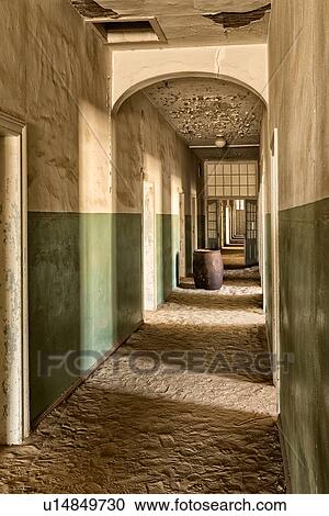 Stock Image - Kolmanskop: interior view of hospital corridor with white and green painted walls, barrel in distance, doorways casting shadows, abandoned German mining town, Namib desert, Namibia, South West Africa. Fotosearch