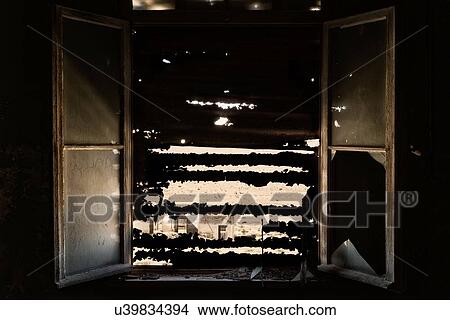 Picture - Kolmanskop interior view of room: window open with broken glass, rusty jagged shutters forming silhouette, close up view, abandoned German mining town, Namib desert, Namibia, South West Africa. Fotosearch