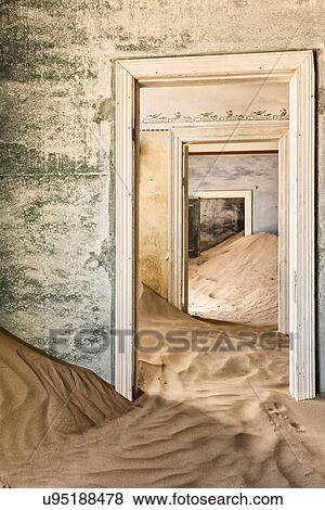 Stock Photo - Kolmanskop interior view of room: doorway with green painted walls leading to other rooms, and sand dune which fills the room, abandoned German mining town, Namib desert, Namibia, South West Africa. Fotosearch