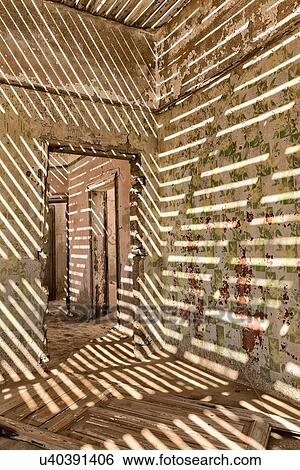 Stock Photograph - Kolmanskop interior view of room: doorway with wall shadows created by roof slats leading to other rooms and sand over floors,, abandoned German mining town, Namib desert, Namibia, South West Africa. Fotosearch