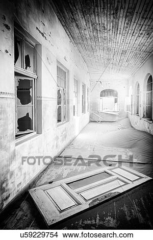 Kolmanskop: interior view of school corridor with broken door lying on floor, broken windows, monochrome view, abandoned German mining town, Namib desert, Namibia, South West Africa View Large Photo Image Picture - Kolmanskop: interior view of school corridor with broken door lying on floor, broken windows, monochrome view, abandoned German mining town, Namib desert, Namibia, South West Africa. Fotosearch