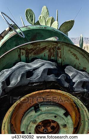 Stock Image - Old tractor detailed side view with green, orange and yellow metal hub around drive wheel, and green weathered metal frame, Namib desert, Namibia, South West Africa. Fotosearch