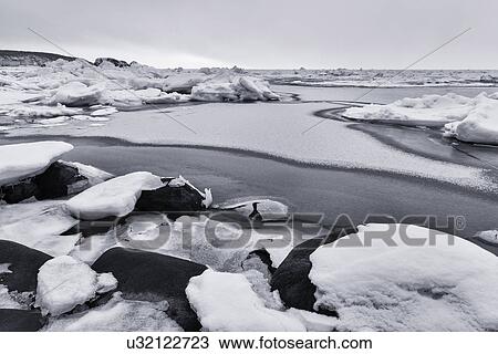 Rocks covered with snow at water's edge, ice patches forming in the frozen sea creating patterns and textures, monochrome image, Shiretoko Peninsula, Hokkaido, Japan View Large Photo Image Stock Image - Rocks covered with snow at water's edge, ice patches forming in the frozen sea creating patterns and textures, monochrome image, Shiretoko Peninsula, Hokkaido, Japan. Fotosearch