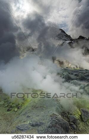 Picture - Sulphuric gases and steam erupting from green and yellow sulphureous rocks at Iouzan volcano, blocking out sunlight beyond, Hokkaido, Japan. Fotosearch