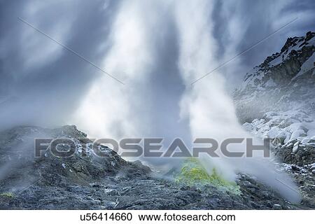 Stock Image - Sulphuric gases and steam erupting from green and yellow sulphureous rocks at Iouzan volcano, blocking out sunlight beyond, Hokkaido, Japan. Fotosearch