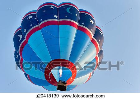 Todi Mongolfiere Hot Air Balloon Festival - red, blue and navy hot air balloon with star pattern rising into sky as seen from directly below, in early morning sunshine, Umbria, Italy View Large Photo Image Stock Photo - Todi Mongolfiere Hot Air Balloon Festival - red, blue and navy hot air balloon with star pattern rising into sky as seen from directly below, in early morning sunshine, Umbria, Italy. Fotosearch