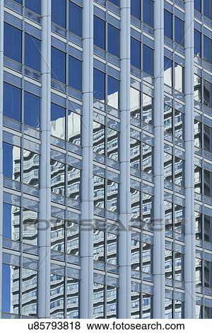 Stock Photo - View of Asago Green Hills, Forest Tower detail with another modern building reflected in the windows, blue sunny sky, Tokyo, Japan. Fotosearch