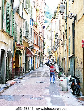 Stock Image - Europe, outdoors, streets, scooter, person, storefronts. Fotosearch