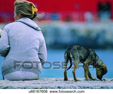 Stock Photo - woman, outdoors, sitting, water, dog, puppy. Fotosearch