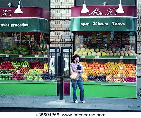 Stock Photography - woman, outdoors, storefront, groceries, telephone, sidewalk. Fotosearch