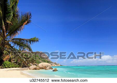 Stock Image - Beach and palm trees, La Digue, Seychelles. Fotosearch