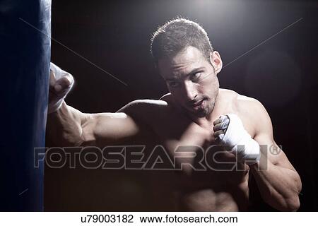 Stock Image - Boxer training with punch bag. Fotosearch