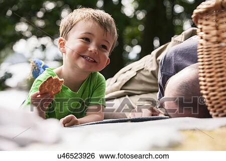 Boy enjoying picnic with father View Large Photo Image Stock Photograph - Boy enjoying picnic with father. Fotosearch
