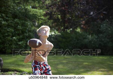 Stock Photo - Boy in garden catching rugby ball. Fotosearch