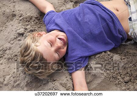 Boy lying on sand laughing, Wales, UK View Large Photo Image Stock Photo - Boy lying on sand laughing, Wales, UK. Fotosearch