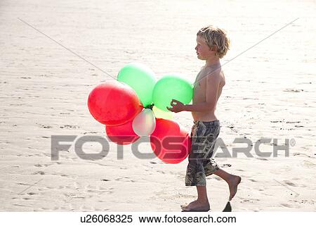 Boy on beach holding balloons, Wales, UK View Large Photo Image Stock Photography - Boy on beach holding balloons, Wales, UK. Fotosearch