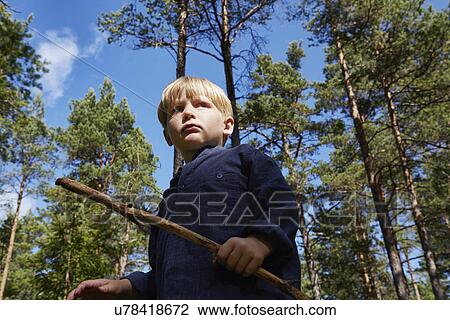Boy standing in forest holding stick View Large Photo Image Stock Image - Boy standing in forest holding stick. Fotosearch