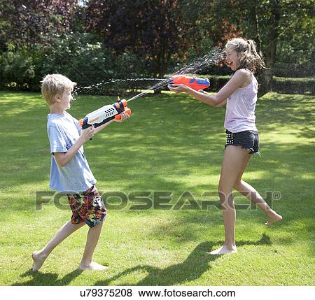 Stock Photo - Brother and sister play fighting with water guns in garden. Fotosearch