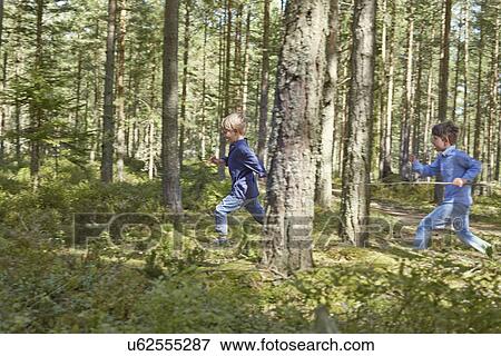 Brothers running through forest carrying sticks View Large Photo Image Stock Photo - Brothers running through forest carrying sticks. Fotosearch