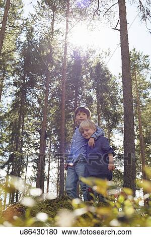Stock Image - Brothers standing in forest with arm around. Fotosearch