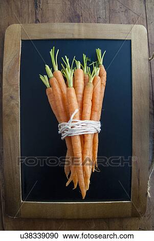 Stock Image - Bunch of carrots on blackboard, still life. Fotosearch