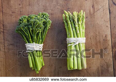 Stock Photo - Bunches of broccoli and asparagus tied with string, still life. Fotosearch
