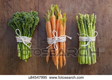 Stock Photography - Bunches of carrots, broccoli and asparagus tied with string, still life. Fotosearch