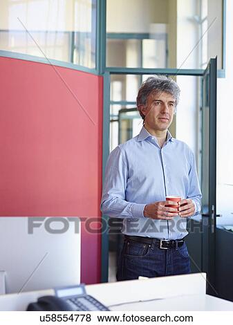 Stock Photo - Businessman holding coffee in office. Fotosearch