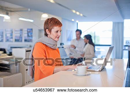 Businesswoman sitting at table using laptop View Large Photo Image Stock Photo - Businesswoman sitting at table using laptop. Fotosearch