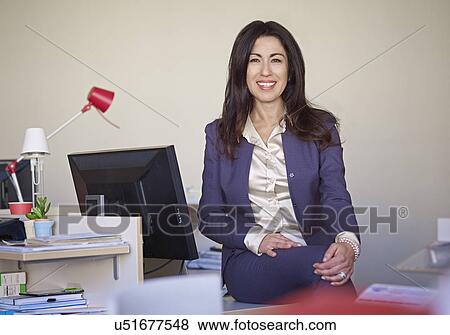 Businesswoman wearing suit sitting at desk View Large Photo Image Stock Photo - Businesswoman wearing suit sitting at desk. Fotosearch