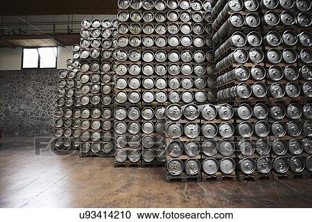 Stock Image - Casks of beer stacked in a brewery. Fotosearch