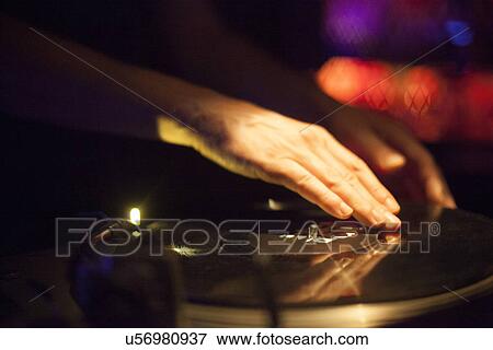 Stock Photo - Close up of DJ's hands spinning vinyl in nightclub. Fotosearch