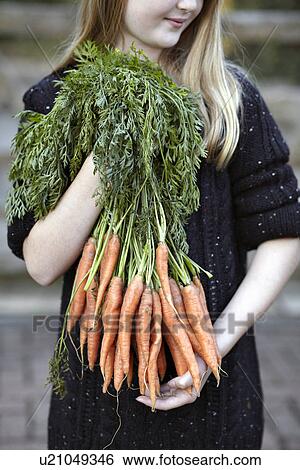 Close up of girl with bunch of carrots View Large Photo Image Stock Photograph - Close up of girl with bunch of carrots. Fotosearch