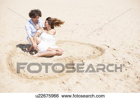Stock Photograph - Couple relaxing on beach. Fotosearch